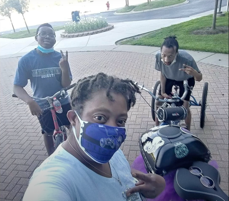 Tiffani Young, a Detroit resident who uses a bike to help meet her mobility needs, poses with two friends and their cycles. Source: Rooted in Rights.