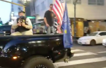A man fires a paintball gun from the back of a Trump-flag-festooned pickup truck in Portland on Saturday.