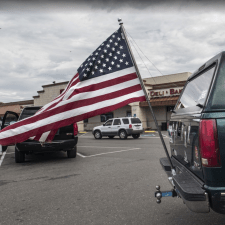 Image description: an American flag attached to the bumper of a large SUV. Source: Robert Couse-Baker, PxHere, CC