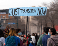 A woman holds a Just Transition Now sign at a rally in Minneapolis, Minnesota.  Image: Lorie Shaull, CC